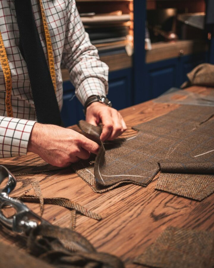 Tailor memotong pola jas di meja kerja kayu