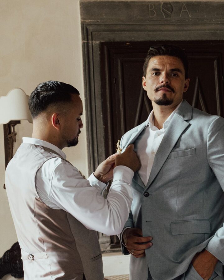 Tailor merapikan kerah jas klien saat fitting
